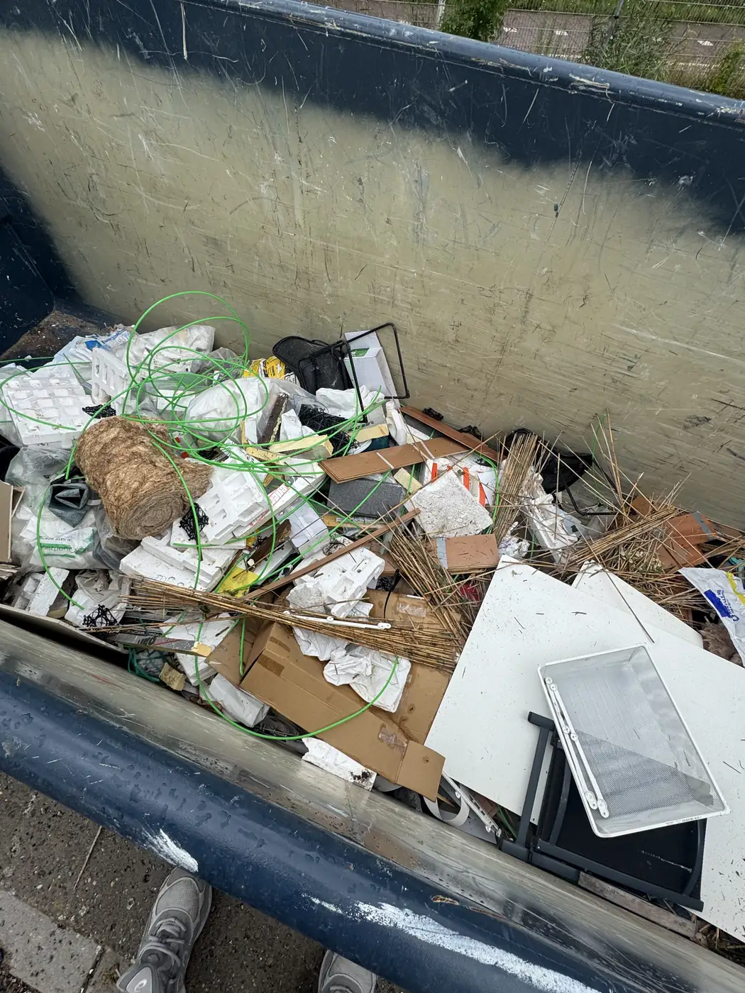 Container gevuld met bouwafval, isolatiemateriaal en tegels na een verbouwing